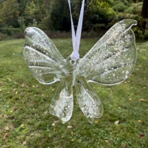 Clear glass butterfly cremation suncatcher with visible ashes suspended throughout the wings and body